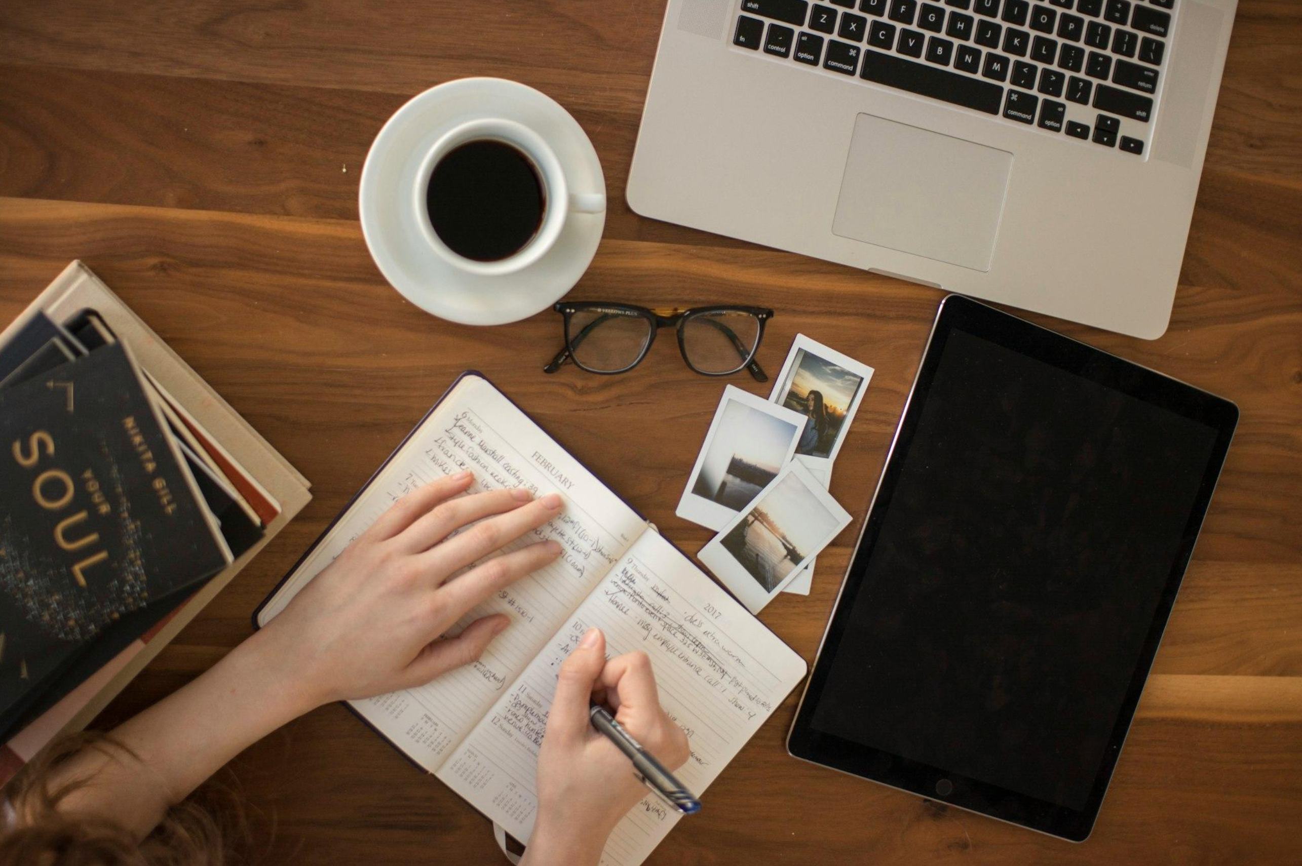 A considered workspace with a notebook, espresso and laptop